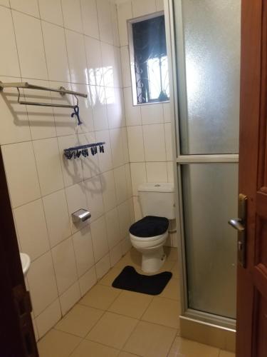 a bathroom with a toilet with a blue seat at Good neighborhood and people around in Kampala