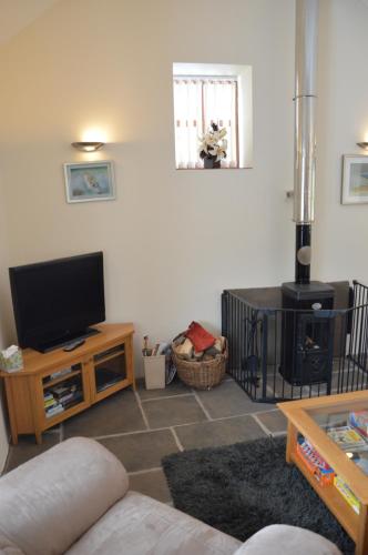 a living room with a flat screen tv on a table at Stone Cottage in Shrewsbury