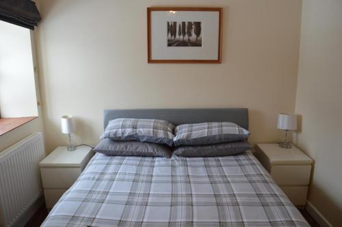 a bed with two pillows and a picture on the wall at Stone Cottage in Shrewsbury