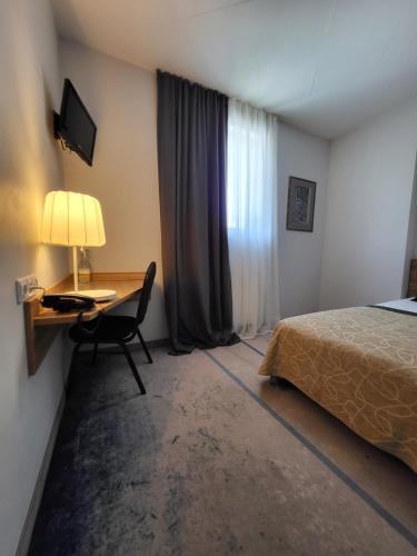 Habitación de hotel con cama y escritorio con lámpara. en Green Vilnius Hotel en Vilna