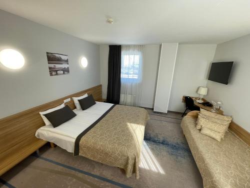um quarto de hotel com uma cama e um sofá em Green Vilnius Hotel em Vilnius