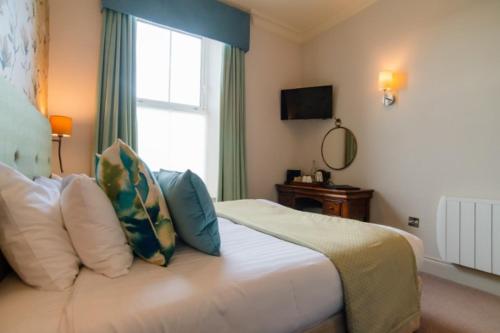 a bedroom with a bed with pillows and a window at Mullion Cove Hotel & Spa in Mullion