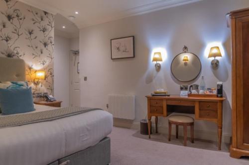 a bedroom with a bed and a vanity and a mirror at Mullion Cove Hotel & Spa in Mullion