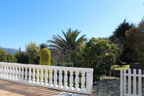 a white fence in front of a yard with trees at finca dos Mares in Ferrol