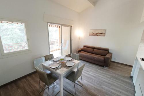ein Wohnzimmer mit einem Tisch, Stühlen und einem Sofa in der Unterkunft Spacious sea view apart at 50m from the beach in Bandol