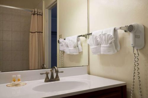 a bathroom with a sink and a mirror and towels at Days Inn by Wyndham San Diego/Downtown/Convention Center in San Diego