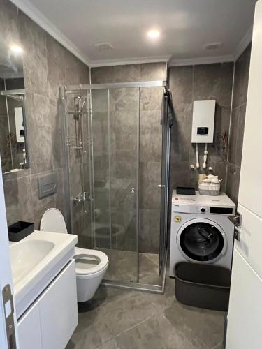 a bathroom with a shower and a washing machine at Magnificent Flat with Shared Pool in Milas in Milas