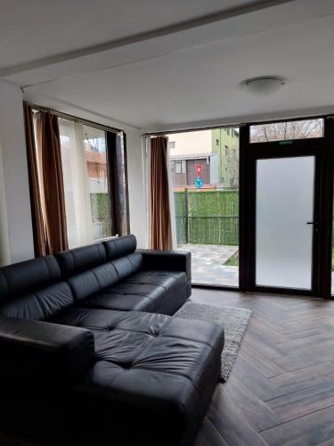- un salon avec un canapé en cuir noir et une grande fenêtre dans l'établissement Ultracentral Apartment Villa ELENA Palas Mall, à Iaşi
