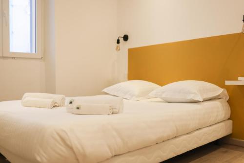 uma cama com lençóis brancos e almofadas em IMMOGROOM - 10 min from the city center - Renovated - Nice and cosy em Cannes