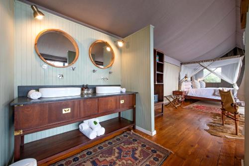 een badkamer met een wastafel en een bed in een kamer bij Camp Figtree by The Oyster Collection in Addo