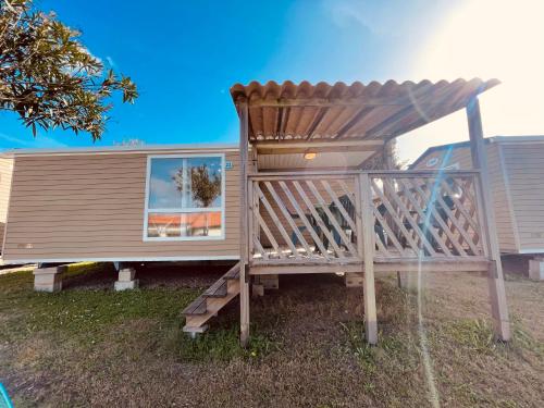 Camping Tonnara في Cala Sapone: سطح خشبي مع شمسية على منزل صغير