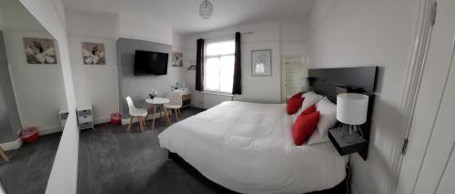 1 dormitorio con 1 cama grande con almohadas rojas en Edelweiss Guest House en Southend-on-Sea