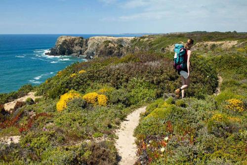 a person with a backpack walking on a trail near the ocean at Boa Vista Hotel & Spa - Adults Only in Albufeira