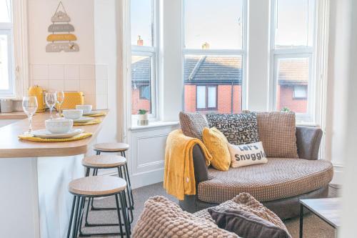 uma sala de estar com um sofá e uma cozinha com janelas em Spacious 3 Bedroom Apartment em Barrow in Furness