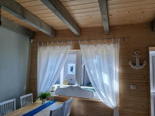 a room with a table and a window with white curtains at Kwiatowe Domki in Rogowo