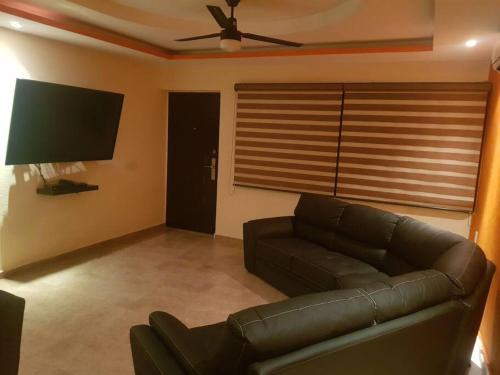 a living room with a couch and a flat screen tv at Departamento en Zona Dorada de Acapulco in Acapulco