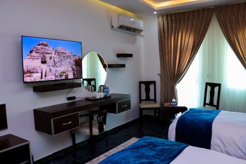 a bedroom with a desk and a tv on a wall at The RN Hotels in Wadi Musa