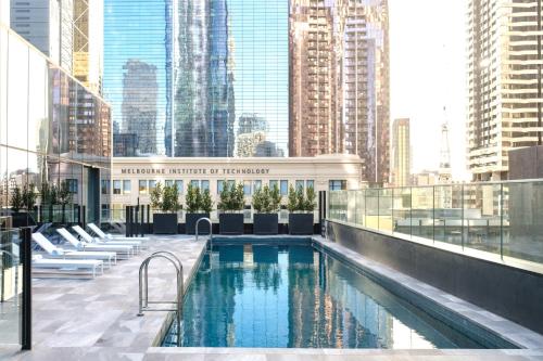 a pool on the roof of a building with tall buildings at Studio Apartments at Aurora near Melbourne Port in Melbourne