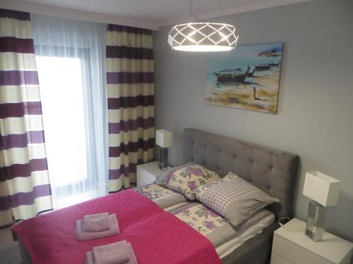 een slaapkamer met een bed met een roze deken bij GARDENIA Apartament Przy Plaży 17 in Dziwnów