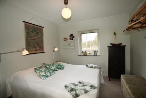 1 dormitorio con cama blanca y ventana en Unique house with Saltwater pool on Gotland, en Romakloster