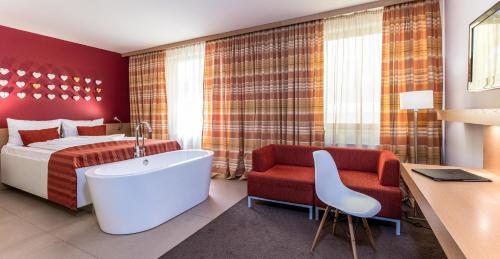 a bedroom with a bed and a tub in a room at Hotel Moserhof in Seeboden