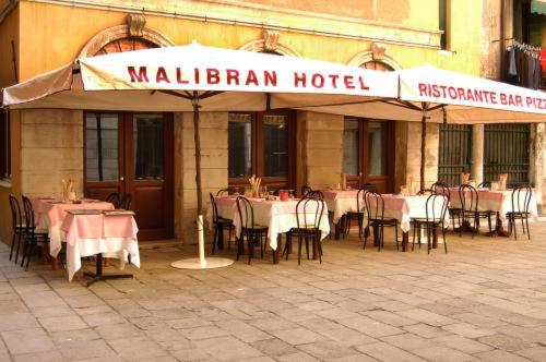 a restaurant with tables and chairs in front of a building at Hotel Malibran in Venice