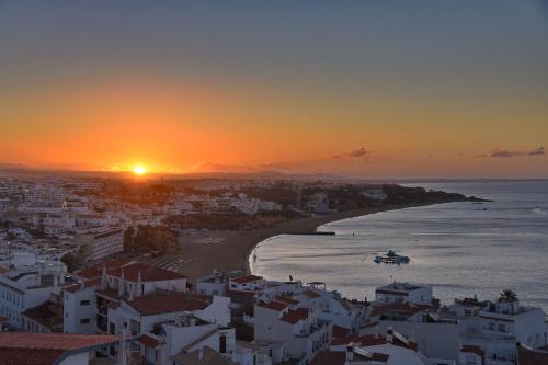 a sunset over a city and a beach with a helicopter at Boa Vista Hotel & Spa - Adults Only in Albufeira