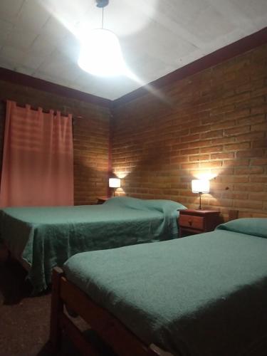 a hotel room with two beds and a brick wall at Sierras Alojamiento in Mina Clavero