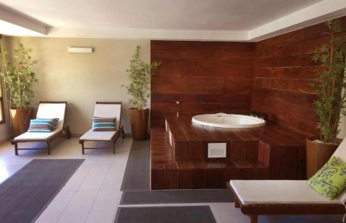 a large bathroom with a tub and two chairs at Jacuzzi Privativa Cobertura no coração de Itaipava in Itaipava