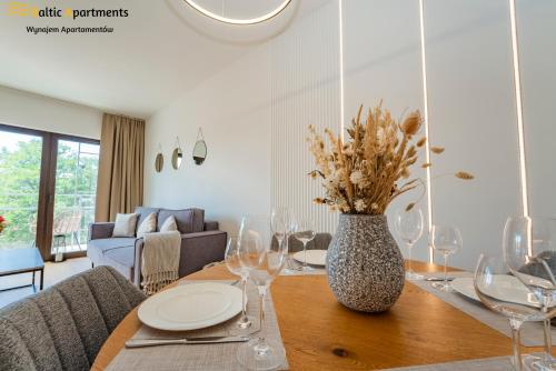a dining room table with wine glasses and a vase with flowers at Baltic Apartments - Kormoran in Świnoujście