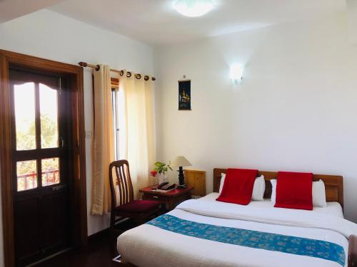 a bedroom with a bed with red pillows and a window at Kathmandu View Hotel in Kathmandu