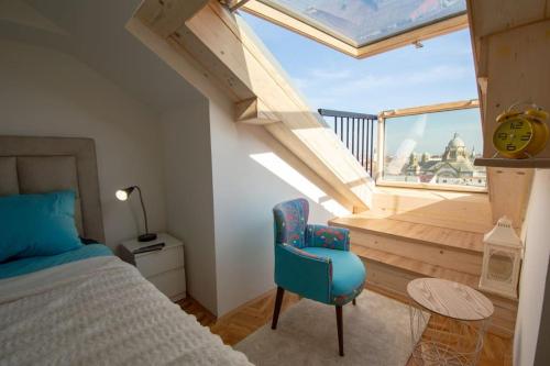 a bedroom with a blue chair and a balcony at Spacious, central and luxury flat with great view! in Novi Sad