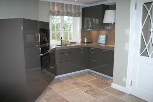 a kitchen with black cabinets and a tile floor at Hotel Duene in Rantum
