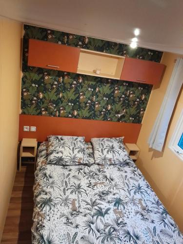 a bedroom with a large bed with a floral wall at location mobil-home in Saint-Chéron