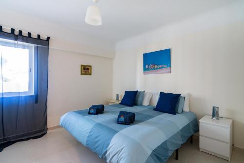ein Schlafzimmer mit einem großen Bett mit blauen Kissen in der Unterkunft Lago Azul 2 in Quarteira