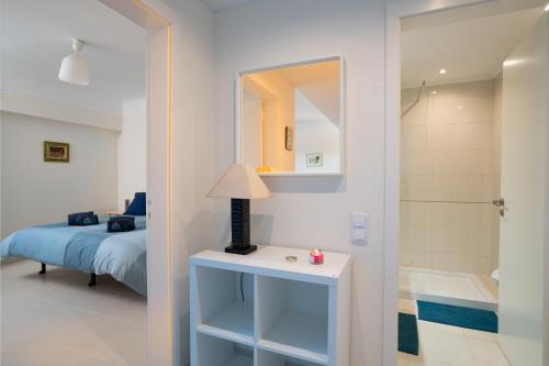 ein Schlafzimmer mit einem Bett und ein Badezimmer mit einem Spiegel in der Unterkunft Lago Azul 2 in Quarteira
