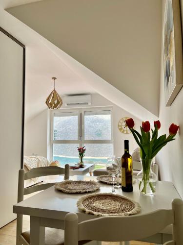 a white dining room with a table with a bottle of wine at Vista apart Pluzine in Plužine