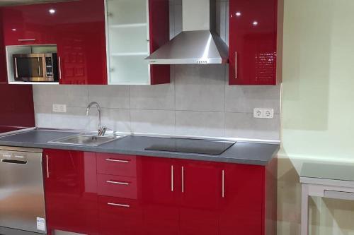 una cocina con armarios rojos y fregadero en Planta superior independiente con piscina - barbacoa, 