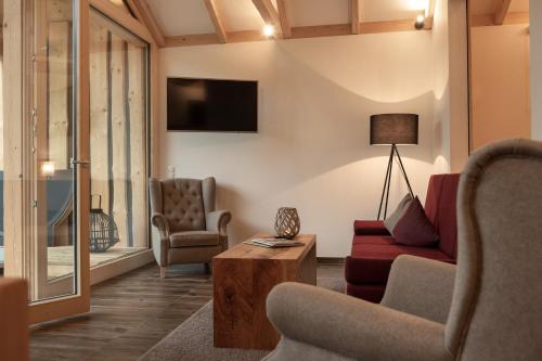 a living room with a couch and chairs and a tv at Forstgut - Premium Waldchalets und Lodge Suiten in Regen