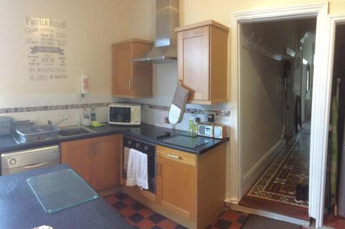 a kitchen with wooden cabinets and a counter top at Turret Corner, Colwyn Bay, 5min walk to sandy beach in Conwy