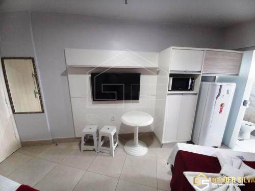 a small kitchen with a refrigerator and two stools in it at CTC Araras Centro in Caldas Novas