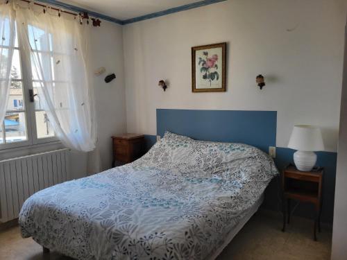 1 dormitorio con 1 cama con cabecero azul y ventana en Villa gitedelea, en Aubignan