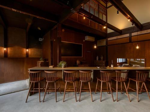 a kitchen with a bar with chairs around it at 長浜城下 町屋ホテル 和乃リトリートひといき in Nagahama