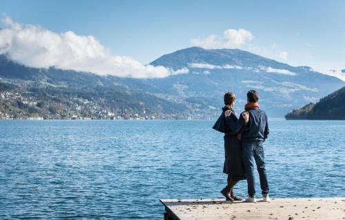 two people standing on a dock looking at a lake at Hotel Moserhof in Seeboden