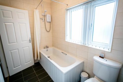 baño con bañera, aseo y ventana en Calder Cottage in The Ribble Valley en Whalley