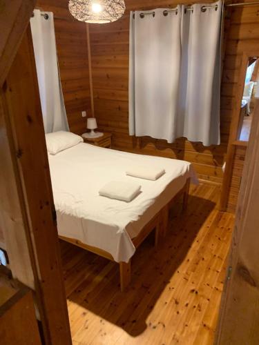 a bed in a wooden room with a window at Arbel Holiday Homes in Arbel