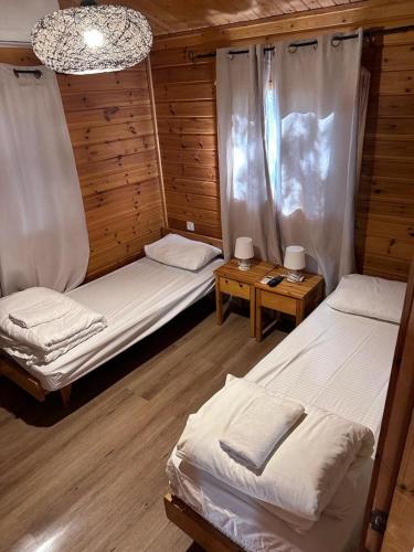 a room with two beds and two tables in a cabin at Arbel Holiday Homes in Arbel
