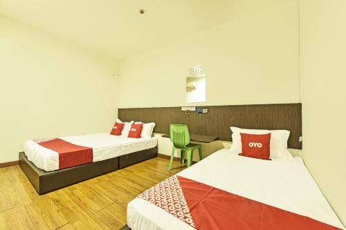 una habitación de hotel con 2 camas y una silla en OYO 90727 Hotel Mini Indah en Kuala Terengganu