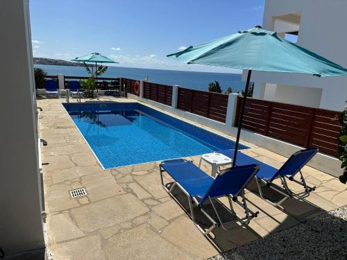 een zwembad met 2 stoelen en een parasol bij Villa Aqua Sunrise 1km From Beach With Sea Views in Coral Bay