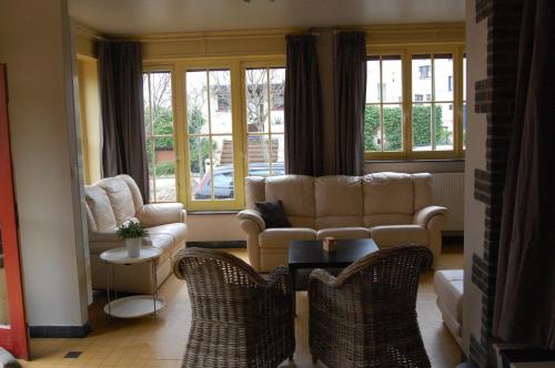 a living room with a couch and chairs and windows at Villa Mowgli in De Panne